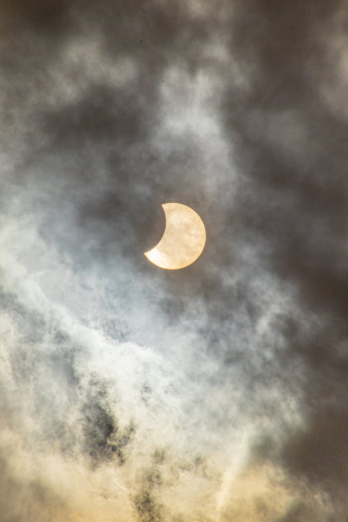 A captivating view of a solar eclipse partially covered by clouds in the sky.